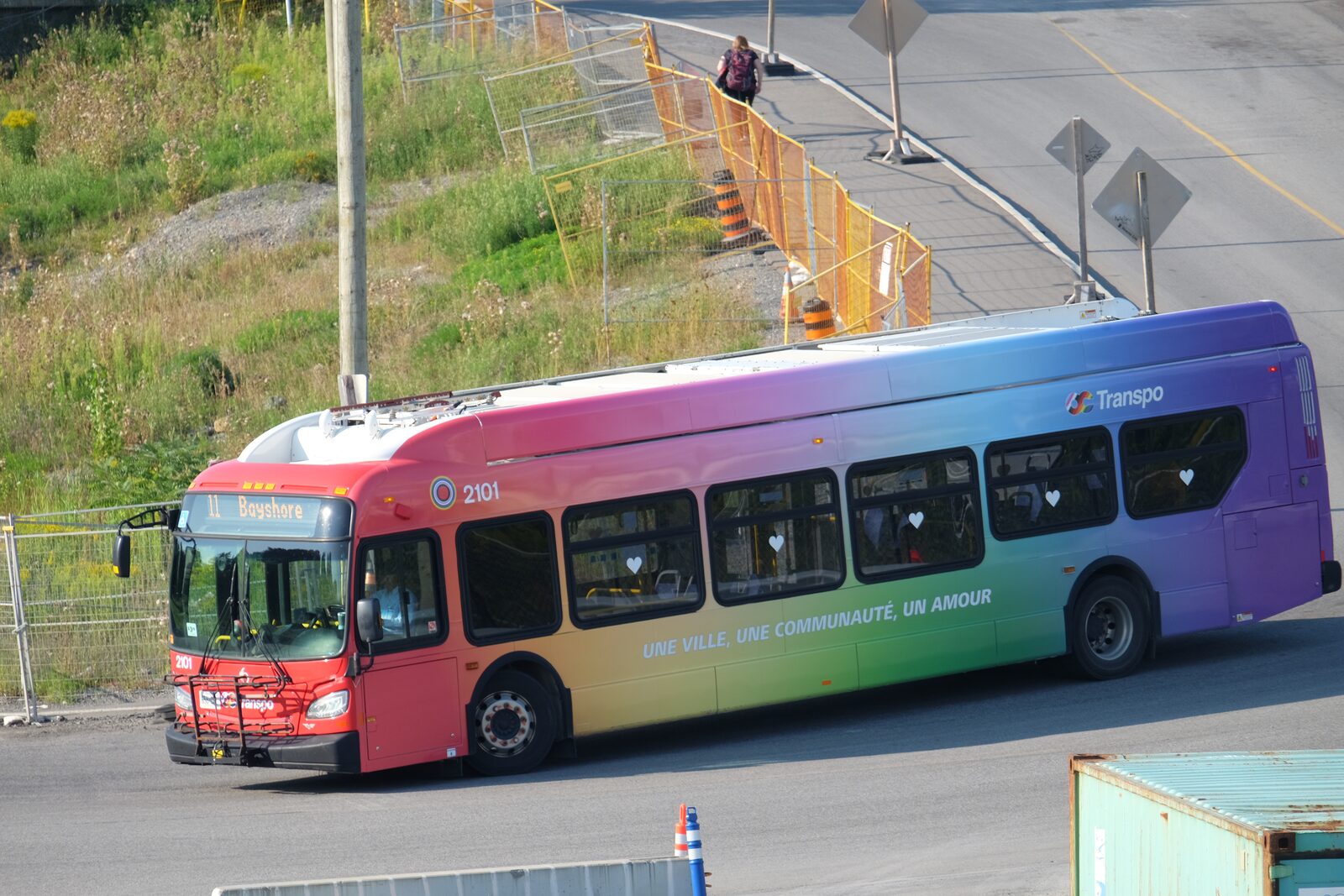 An OC Transpo New Flyer electric bus in a community-pride livery entering the transitway (2024).